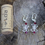 Clear crystal barbell shaped beaded earrings with ruby-colored Swarovski crystals and sterling lever back ear wires. Cork for size reference