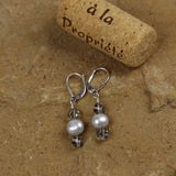 Earrings with silvery freshwater pearls and gray Swarovski crystals on sterling silver lever back ear wires. Cork for size reference.