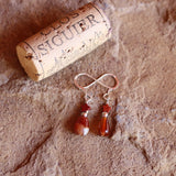 Red agate drop with red jasper star earrings on sterling silver ear wires. Cork for size reference.