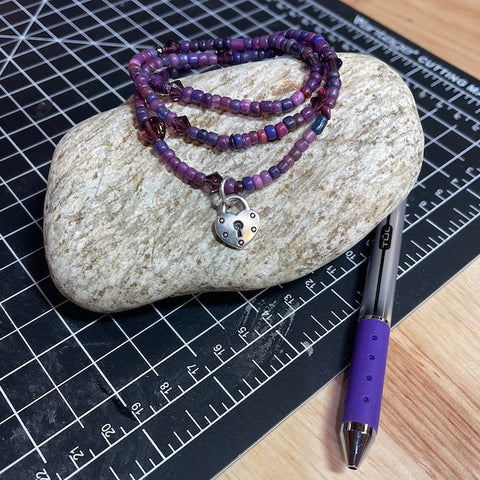 Stretch necklace or triple wrap bracelet with purple beads and a heart padlock charm