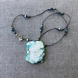 Turquoise-tinted calcite stone pendant with Swarovski crystals and gunmetal-plated bronze beads on hand-knotted cord.