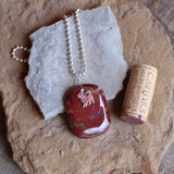 Glossy red agate stone pendant with sterling puppy charm on sterling ball chain. Cork for size reference