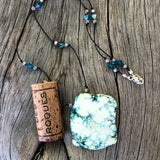 Turquoise tinted calcite slab pendant necklace with Swarovski crystals on hand-knotted cord. Cork shown for size reference.