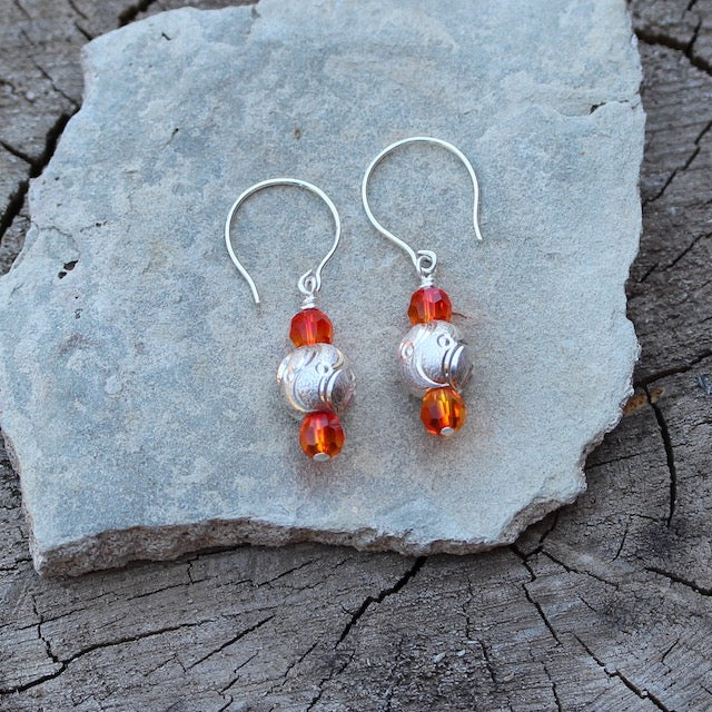 Sterling laser-cut bead earrings with orange Swarovski crystals. Intricate swirling patters are laser cut into the surface of the sterling beads which are framed with orange Swarovski crystals.