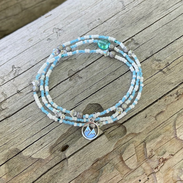 A versatile stretch necklace that can also be worn as a triple wrap bracelet. Sterling mountains charm with aqua and white seed beads and sparkling crystals.