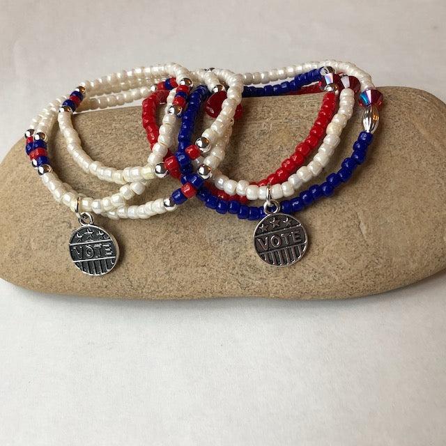 Stretch necklace or triple wrap bracelet with silver VOTE charm and red white and blue seed beads.