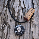 Black and gray striped agate stone pendant necklace with silver sugar skull charm on twisted rubber cord. Cork for size reference.