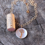 Bronze key with pearly shell pendant on 14k gold filled chain. Cork for size reference.