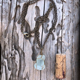 Bronze wire-wrapped sea glass pendant necklace on bronze double chain. Cork for size reference.