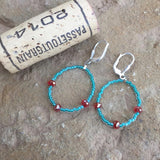 Flexible hoop earrings with turquoise seed beads and orange crystals with cork for size reference