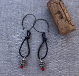 Bohemian style leather loop earrings with intricate Thai silver beads and Swarovski crystals. Cork for size reference.