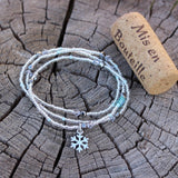 Stretch necklace or triple wrap bracelet with snowflake charm and clear seed beads. Cork for size reference.