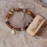 Golden amber nuggets stretch bracelet with sterling silver accent beads and a sterling compass charm. Cork shown for size reference.