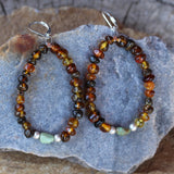 Flexible hoop earrings with amber beads and a single turquoise bead highlighted with satin finish sterling beads. Sterling silver lever back ear wires.
